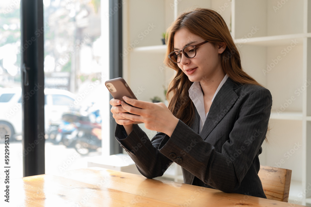 Smiling businesswoman using a phone in the office. Small business entrepreneur looking at her mobile phone and smiling. Smiling businesswoman using a phone in the office. Small business entrepreneur looking at her mobile phone and smiling.