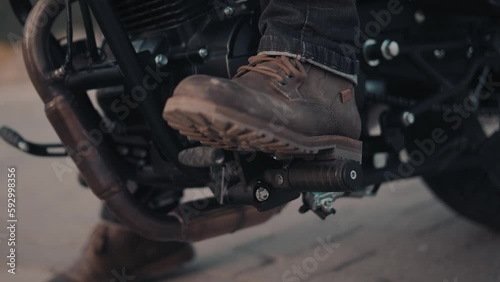 The biker presses the gas pedal of the motorcycle and drives away. Close-up.
