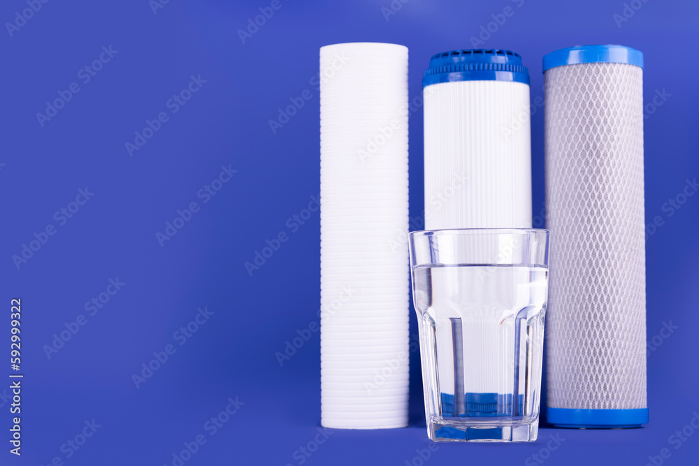 set three of cartridges for water filter with clear glass of water isolated on violet background. Concept of water treatment technology. filter cartridges to domestic water treatment systems.