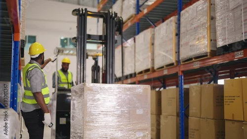 Retail Warehouse full of Shelves with Goods: Electric Forklift Truck Operator Lifts Pallet with Cardboard Boxes On a Shelf. People Working, Scanning Products, Using Trucks in Distribution Center