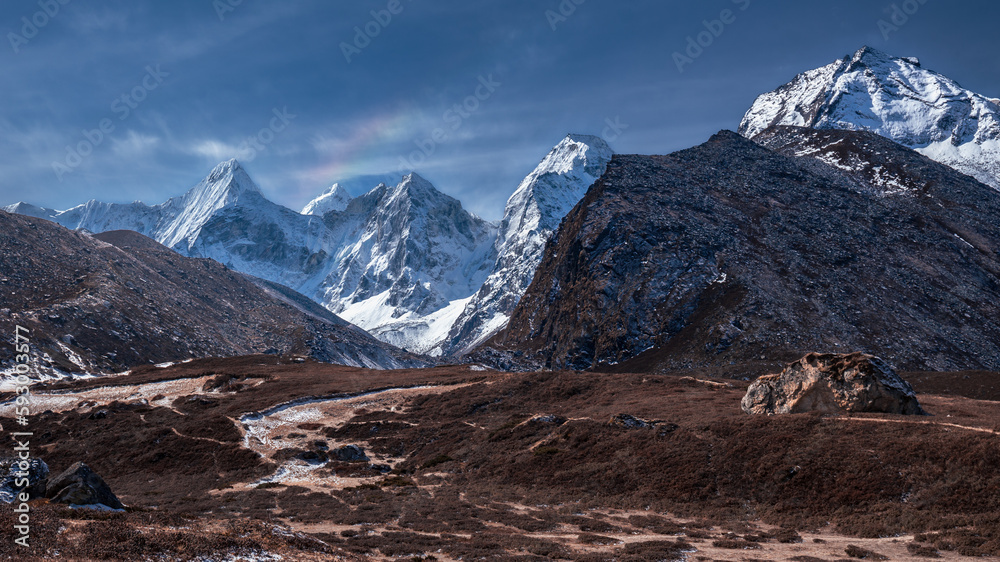 Panoramic landscape with valley against backdrop of snowy mountains in sunlight, Nepal, Himalayas