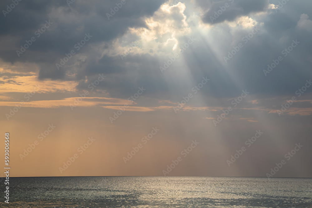 Beautiful rays of light fall into the sea. Cloudy sky. Beautiful light. Sea water. Evening light.