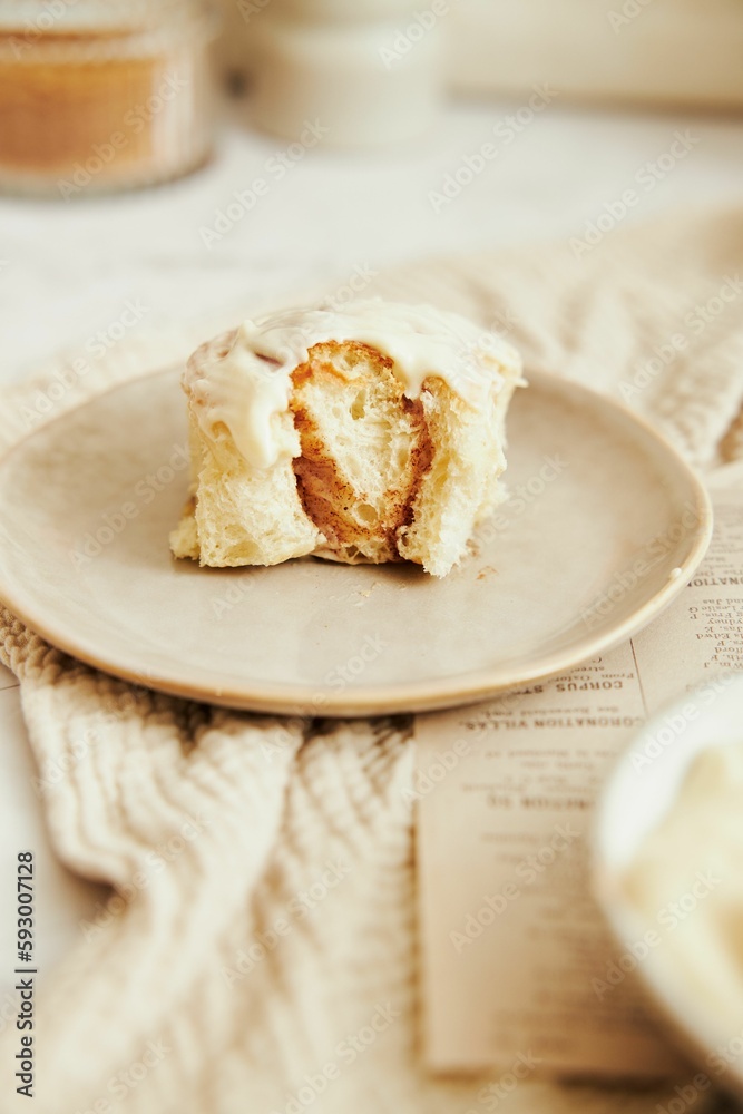 Vertical shot of delicious cinnamon Buns with cream on a white table Vertical shot of delicious cinnamon Buns with cream on a white table