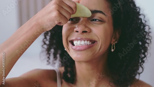  Gua Sha face lifting massage concept. Young african american woman massaging face with gua sha stone and smile. self beauty concept