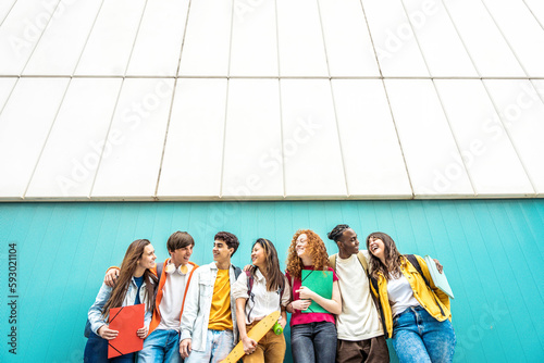 Diverse college students standing together in university campus - Multiracial teenagers chatting and laughing outdoors - Life style concept with guys and girls going to highschool photo