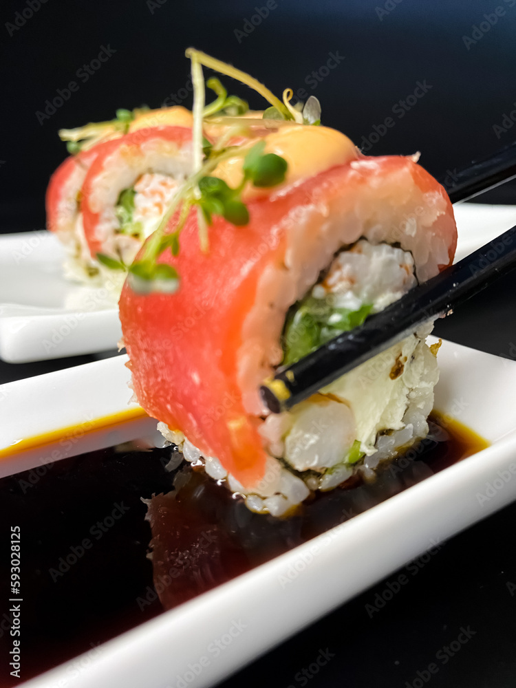 sushi and rolls on the white Japanese plate on black background sushi and rolls on the white Japanese plate on black background