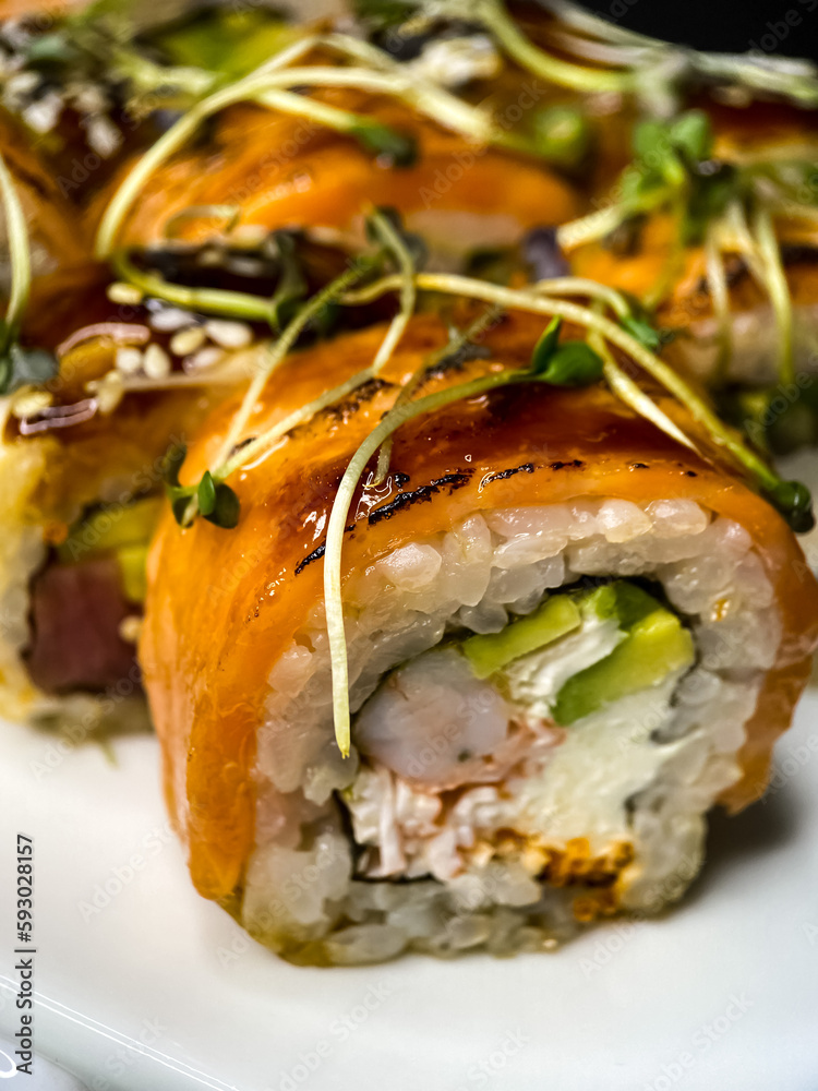 sushi and rolls on the white Japanese plate on black background sushi and rolls on the white Japanese plate on black background