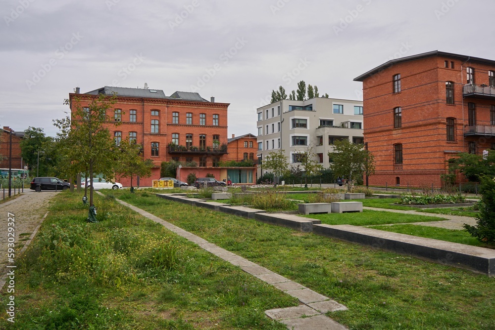 Obraz premium Beautiful garden in Berlin with residential buildings in the background under gray sky