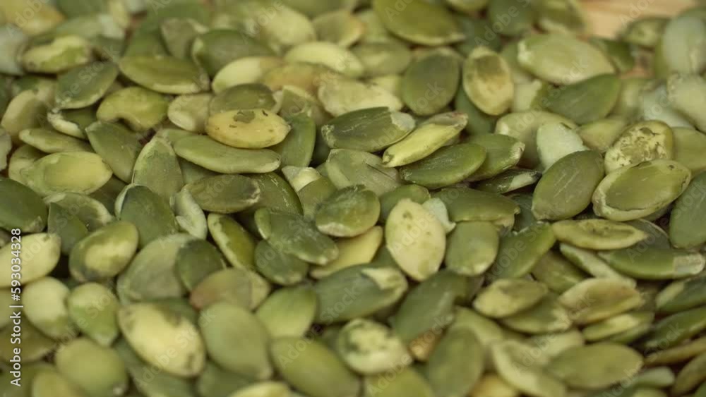 Peeled Pumpkin Seeds Pile Rotating on a Wooden Cutting Board. Healthy Vegetarian Vegan Raw Food Peeled Pumpkin Seeds Pile Rotating on a Wooden Cutting Board. Healthy Vegetarian Vegan Raw Food