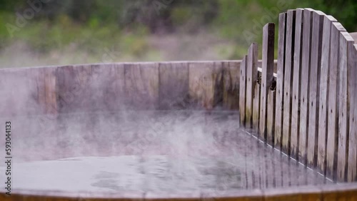 Hot wood barrel bathtub in the nature at winter. Water steam rising in slow motion.