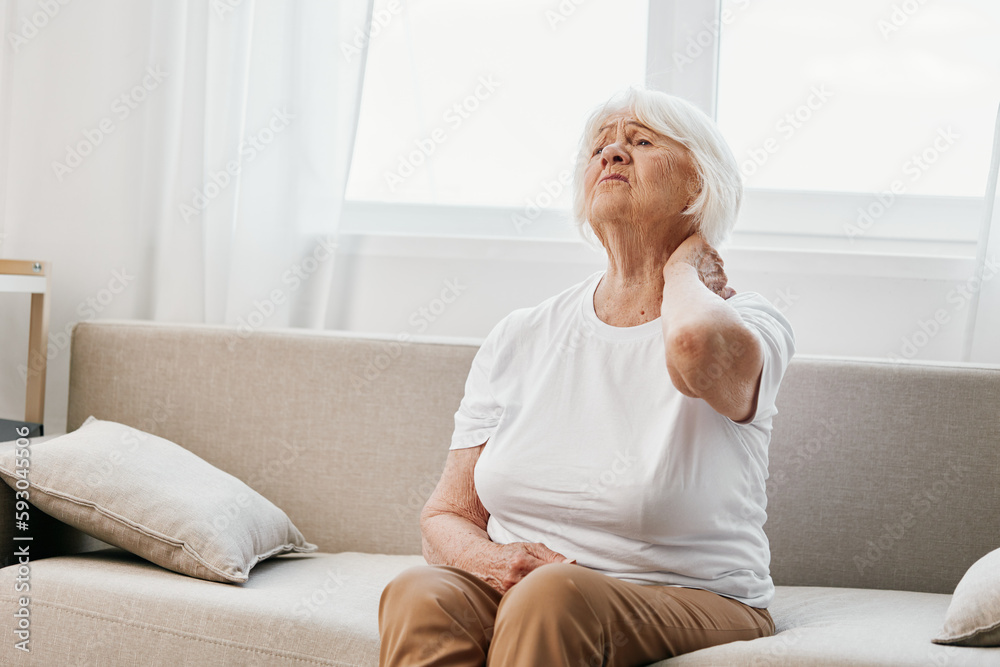 Elderly woman severe neck pain sitting on the sofa, health problems in old age, poor quality of life. Elderly woman severe neck pain sitting on the sofa, health problems in old age, poor quality of life.