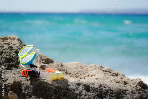 snorkel set on a rock with the ocean in the background with copy space in summertime. Holidays background