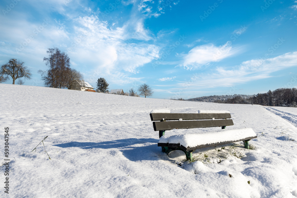 Empty bench covered in snow in a field on a clear winter sunny day Empty bench covered in snow in a field on a clear winter sunny day