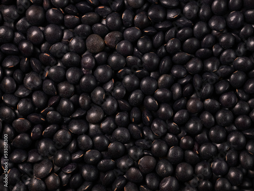 Black lentils texture food background. Dry beluga lentil grains pattern, raw dal, daal, dhal, masoor, pulse wallpaper with copy space. Top view from above