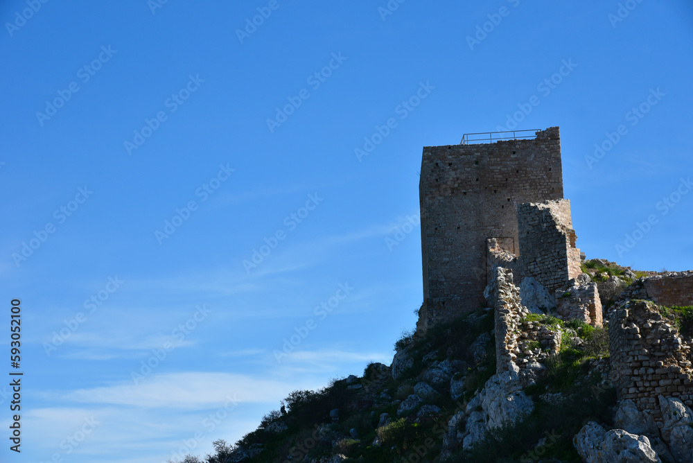 Palamidi Castle walls built high on the crest of a hill above the old Nafplio city. View of ruins of one of fortress bastions, harbor, green coastal plains and distant mountains. Peloponnese, Greece.
