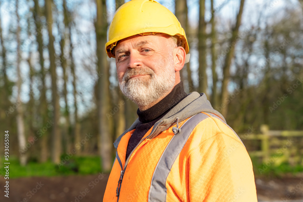 Portrait of a builder in orange hi-viz and helmet smiling into the camera Portrait of a builder in orange hi-viz and helmet smiling into the camera