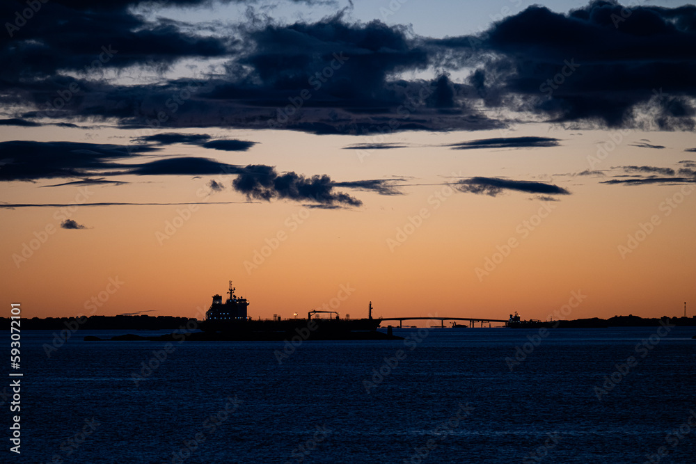 Silhouette of tanker ships and a bridge in sunset light.
