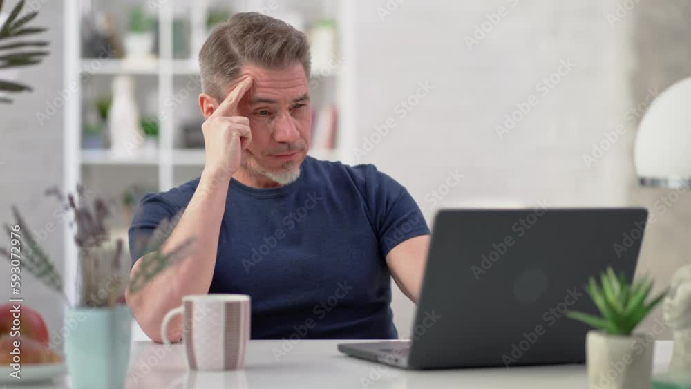 Bearded man working online with laptop computer at home sitting at desk. Businessman in home office, browsing internet. Portrait of mature age, middle age, mid adult man in 50s. Bearded man working online with laptop computer at home sitting at desk. Businessman in home office, browsing internet. Portrait of mature age, middle age, mid adult man in 50s.