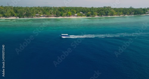 Aerial drone footage of speedboat on turquoise lagoon and coral reef of Gili Meno tropical island, Indonesia  photo