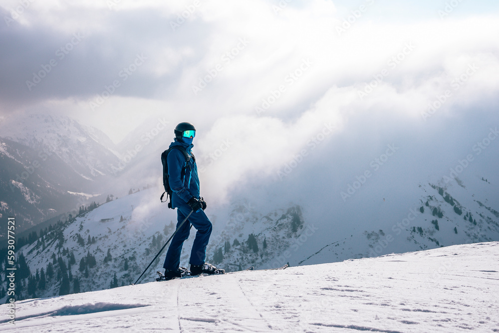 Tourist with ski poles skiing on snow covered mountain with cloudy sky in background during winter vacation, winter holiday travel concept Tourist with ski poles skiing on snow covered mountain with cloudy sky in background during winter vacation, winter holiday travel concept