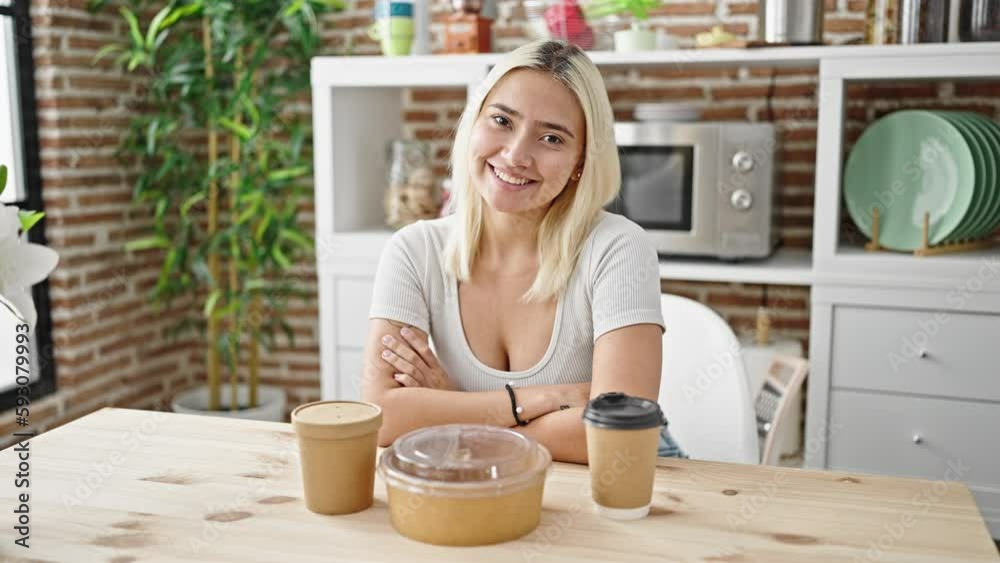 Young beautiful hispanic woman sitting on table with take away food at dinning room Young beautiful hispanic woman sitting on table with take away food at dinning room