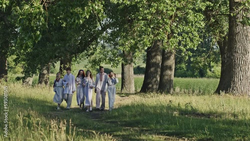 Friends dressed in Ukrainian folk clothes walk along path photo