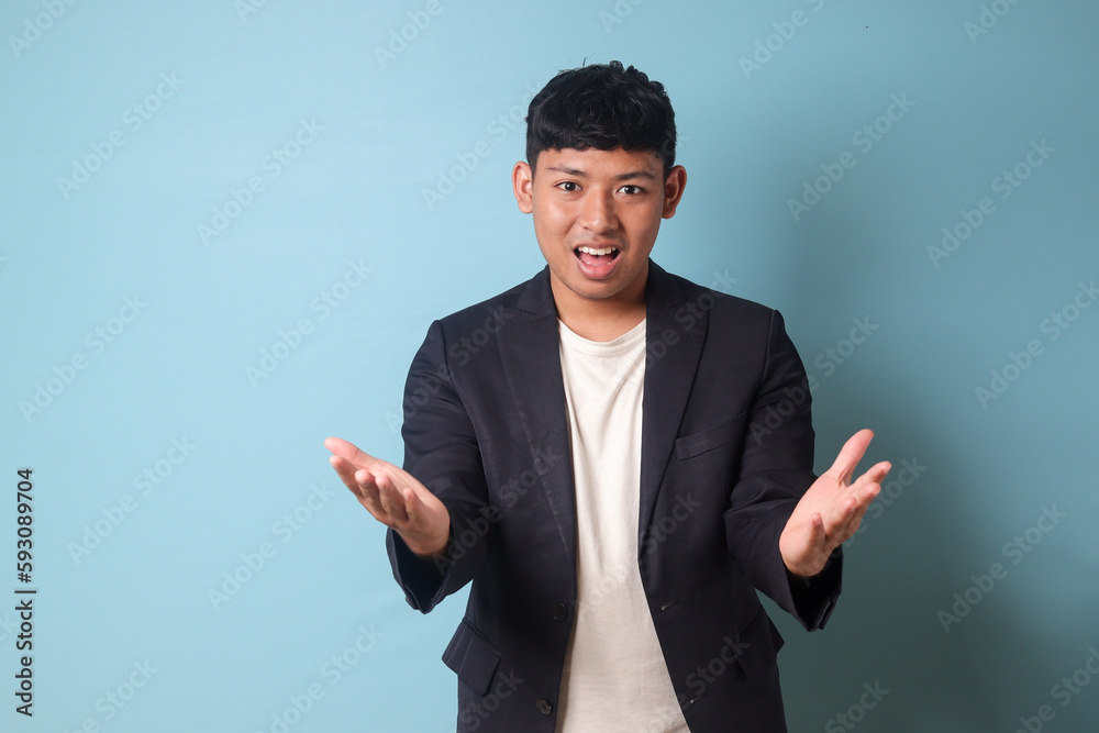 Portrait of young Asian business man in casual suit presenting happily with full confidence. Isolated image on blue background Portrait of young Asian business man in casual suit presenting happily with full confidence. Isolated image on blue background