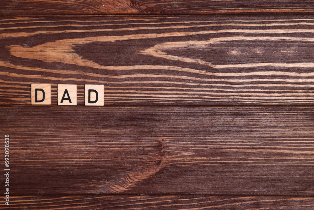 Word dad, lettering on wooden background Word dad, lettering on wooden background