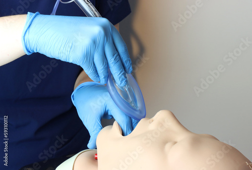 Laryngeal mask airway (LMA) Bering inserted in a simulated patient airway by a health care professional wearing gloves and surgical scrubs  photo