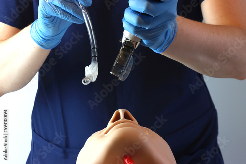 Health care professional holding a laryngoscope and a endotracheal tube simulation a prepared professional for intubating a simulated patient  photo