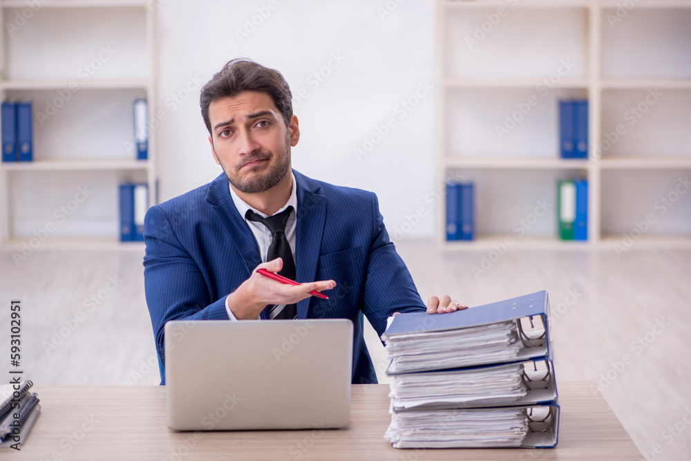 Young male employee and too much work in the office Young male employee and too much work in the office