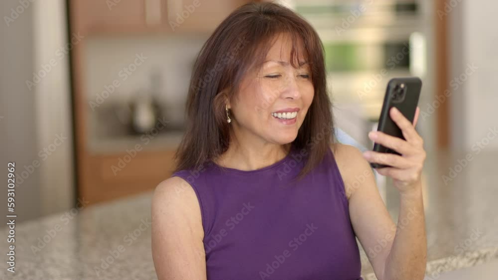 Closeup cheerful attractive woman smiling enjoying video chat using mobile cell phone in kitchen Closeup cheerful attractive woman smiling enjoying video chat using mobile cell phone in kitchen