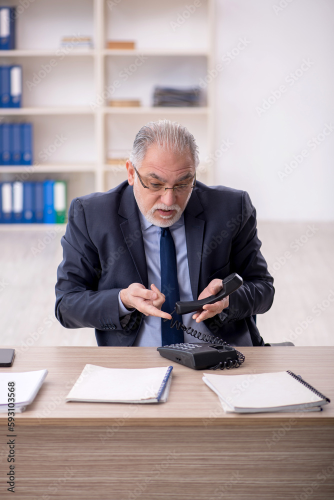 Old male employee working in the office Old male employee working in the office