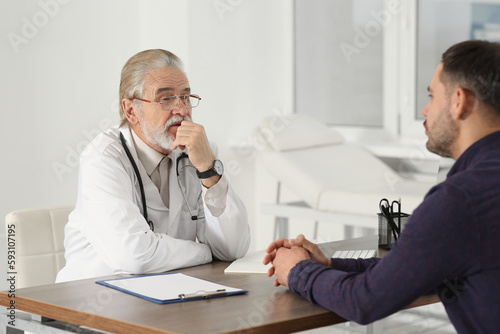 Senior doctor consulting patient at wooden table in clinic © New Africa