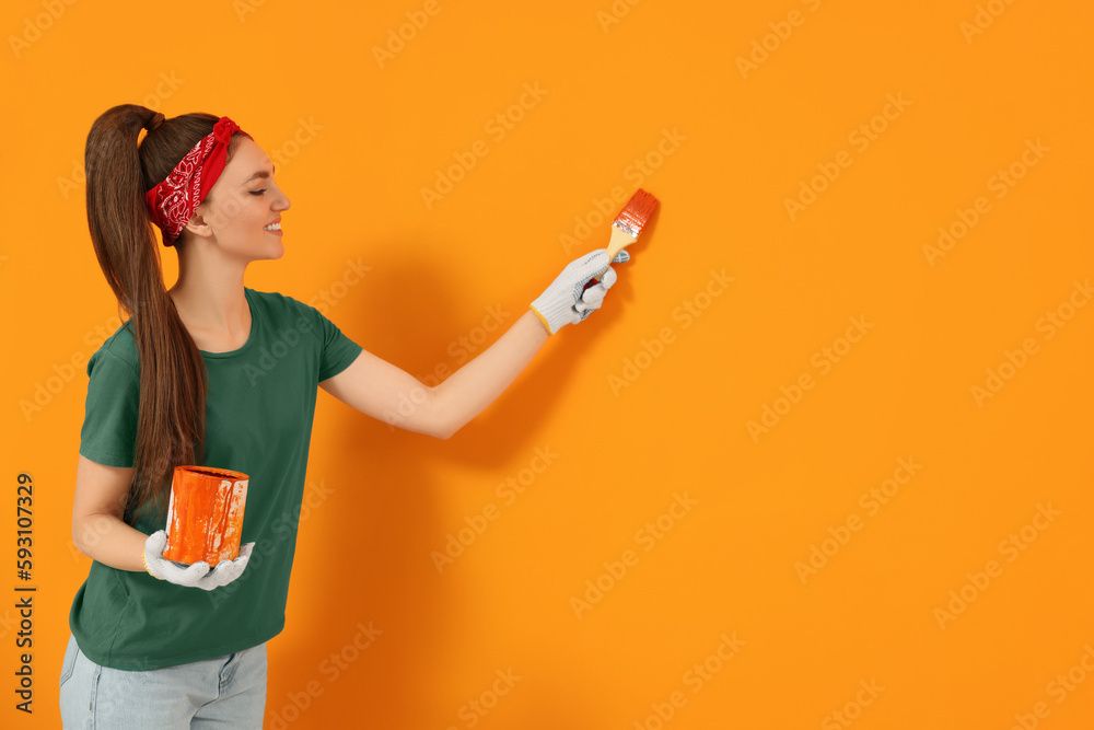 Designer painting orange wall with brush, space for text Designer painting orange wall with brush, space for text