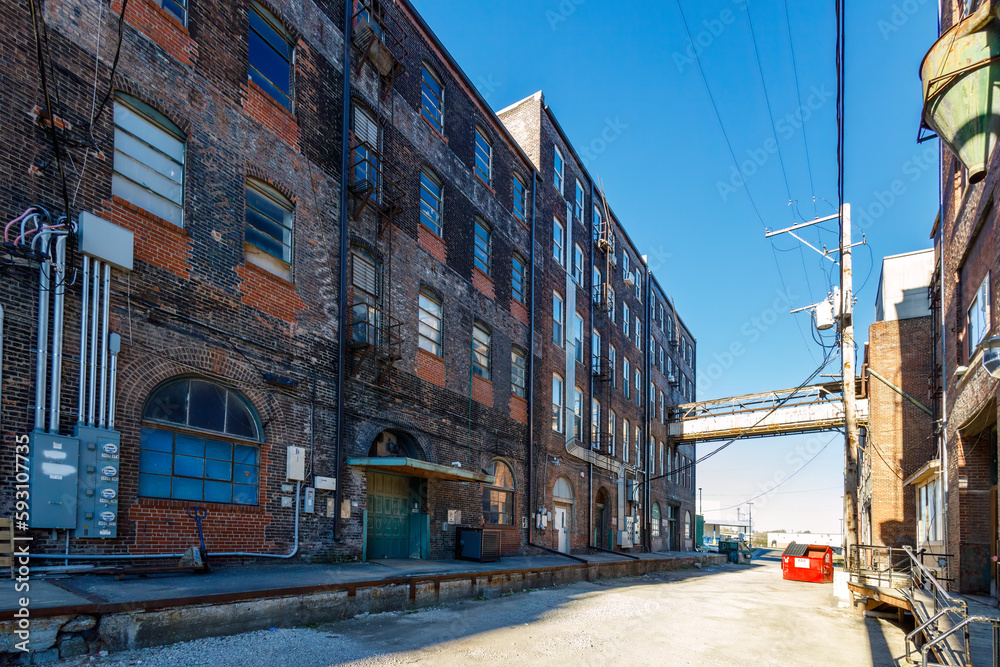 view from the alley of an old warehouse from the 1800's with many windows on a sunny day