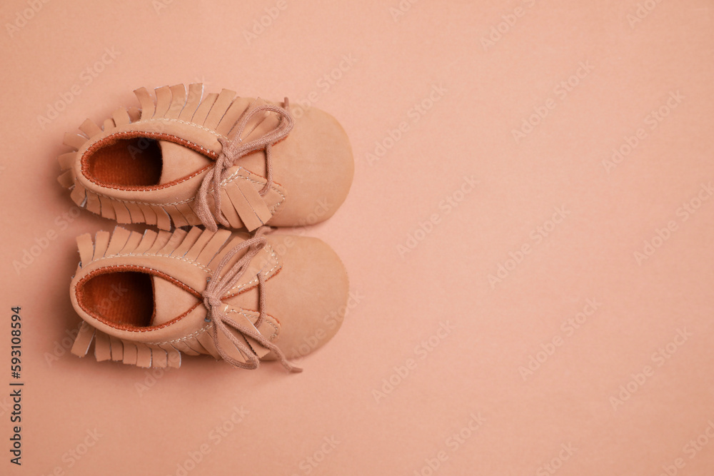 Naklejka premium Cute baby shoes on brown background, flat lay. Space for text