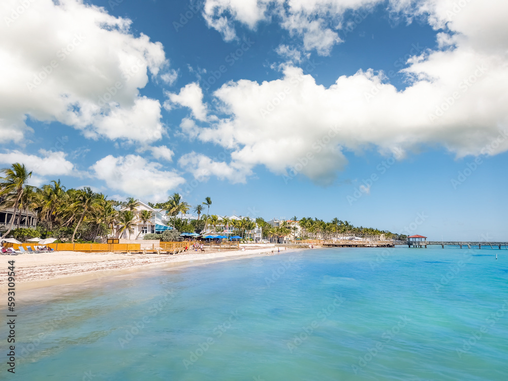 Tropical sandy beach in Key West, Florida with unidentifiable tourists enjoying the sunny warm weather. Tropical sandy beach in Key West, Florida with unidentifiable tourists enjoying the sunny warm weather.
