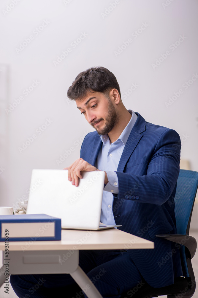 Young male employee sitting at workplace Young male employee sitting at workplace