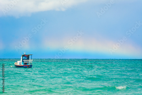 Snapshot of a rainbow over the sea on a sunny day with blue sky
