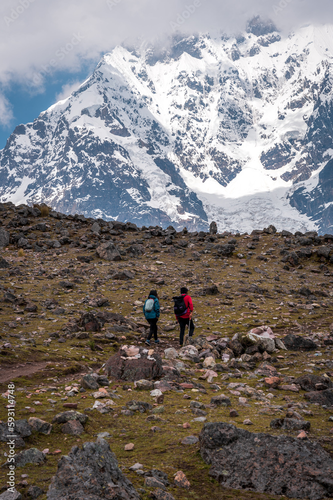 Young hikers on the ausangate circuit in front of the snow-covered peak, Ausangate 6384m, Cordillera Vilcanota, Peru, South America