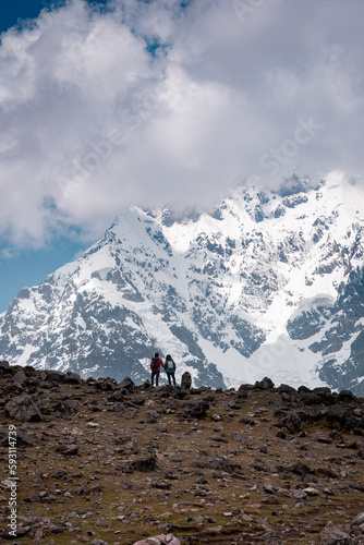 Young hikers on the ausangate circuit in front of the snow-covered peak, Ausangate 6384m, Cordillera Vilcanota, Peru, South America
