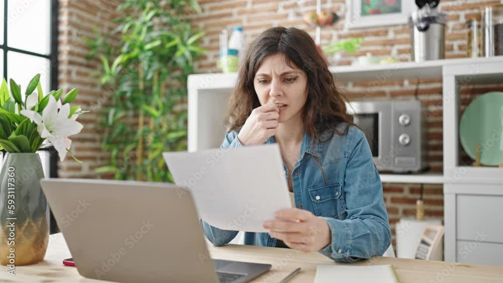 Young beautiful hispanic woman reading document with angry expression at dinning room