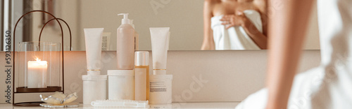 Canvas Print Charming woman sitting near cosmetic products in spa salon