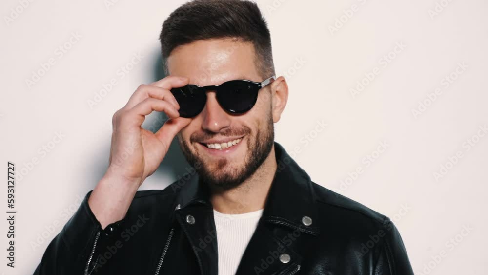Closeup portrait of handsome model. Sexy stylish man dressed in biker leather jacket and black jeans. Fashion hipster male isolated on white in studio. sunglasses Closeup portrait of handsome model. Sexy stylish man dressed in biker leather jacket and black jeans. Fashion hipster male isolated on white in studio. sunglasses