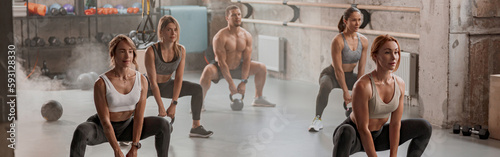 Obraz na plátně Group of people exercising with kettlebells at gym