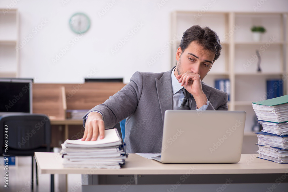 Young male employee unhappy with excessive work in the office Young male employee unhappy with excessive work in the office