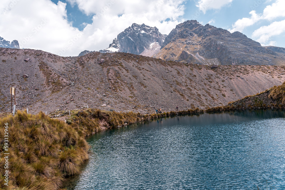 Photos of the tranquil turquoise lake and admiring the snow-capped Ausangate mountain peaks on a sunny day in Peru.