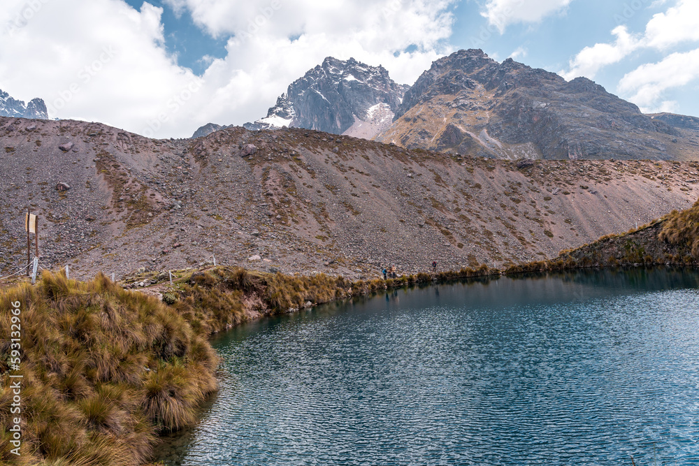 Naklejka premium Photos of the tranquil turquoise lake and admiring the snow-capped Ausangate mountain peaks on a sunny day in Peru.