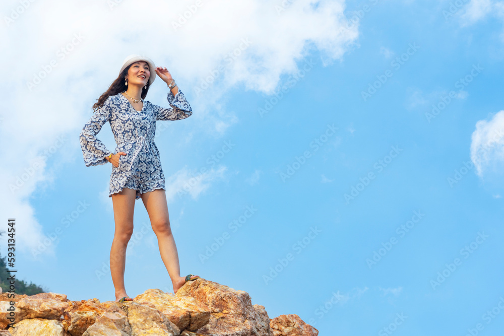 Naklejka premium Female tourist backpacker in hat hiking up the hill adventurous walking up the hill standing view on the hill by the sea during summer time